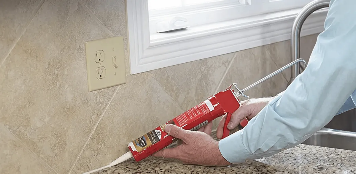 Handyman applying caulk along a kitchen backsplash and countertop seam in San Diego, CA