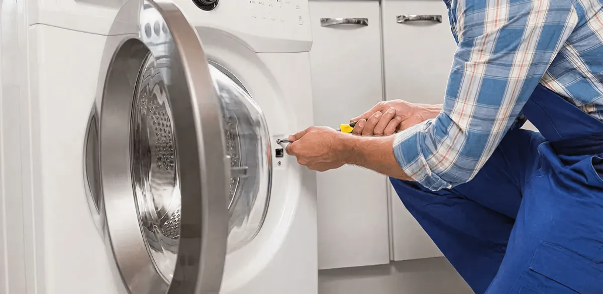 Handyman repairing a clothes dryer and checking electrical connections in San Diego, CA