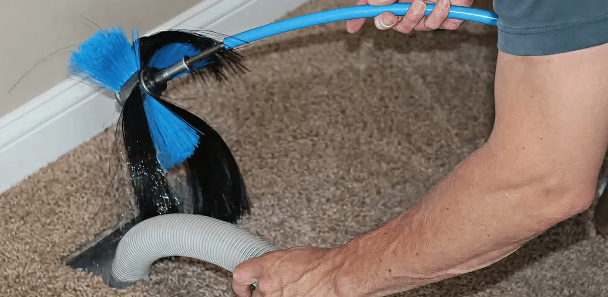 Dryer vent cleaning technician brushing lint from a vent line in San Diego, CA